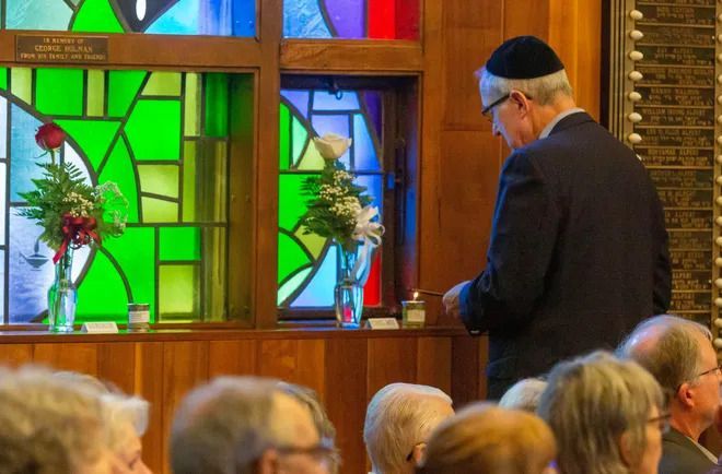 A man in a suit is standing in front of a stained glass window in a church.