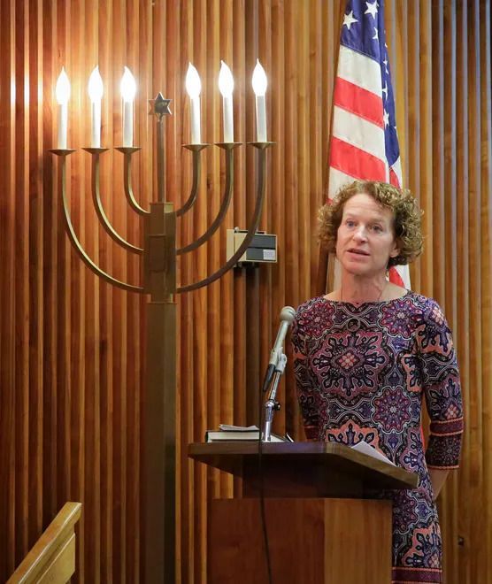 A woman stands at a podium in front of an american flag