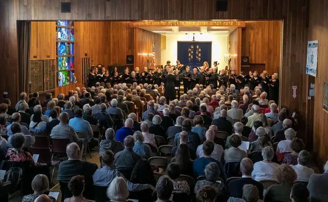 A large group of people are sitting in a church watching a concert.