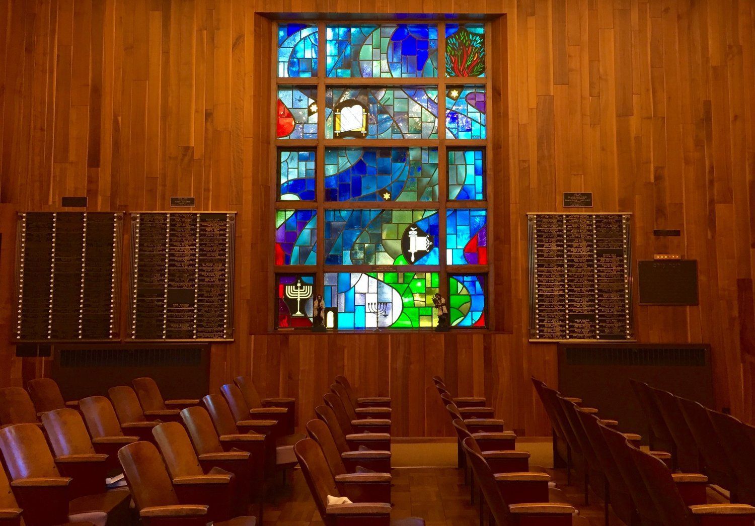 A church with a stained glass window and rows of chairs