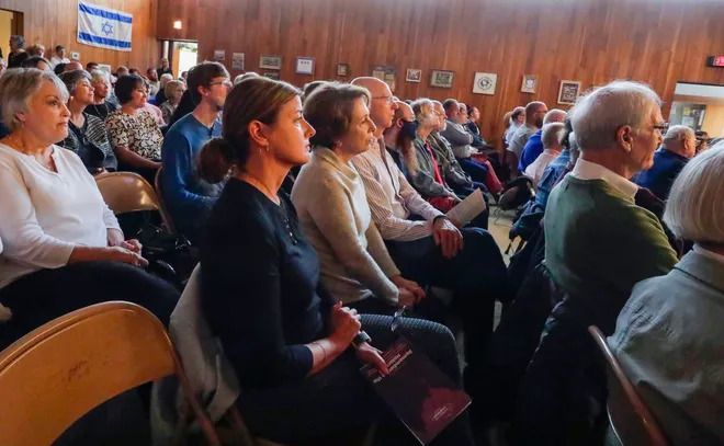 A large group of people are sitting in chairs watching a presentation.