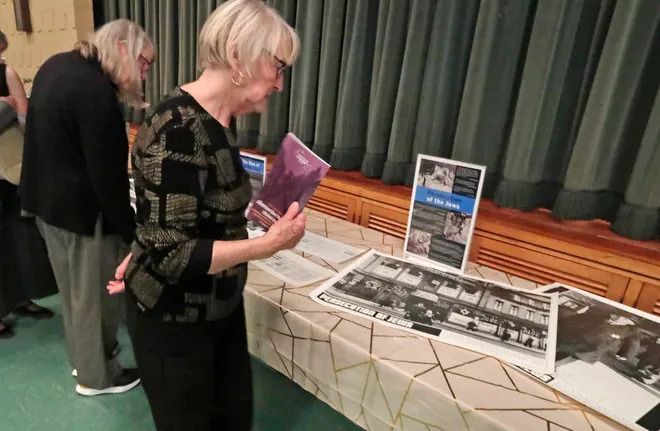 Two women are looking at pictures on a table.