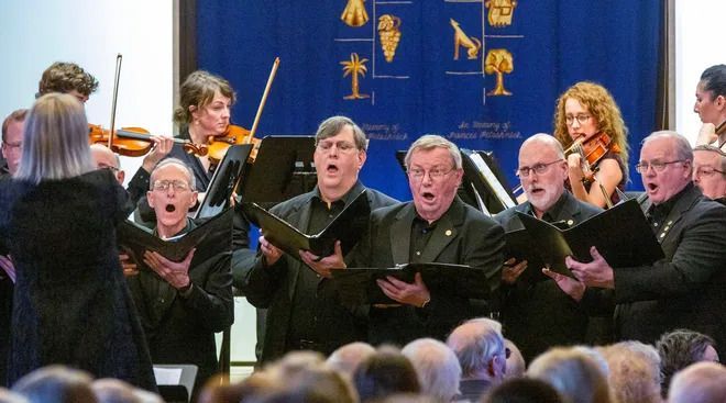 A choir is singing in front of a crowd of people.