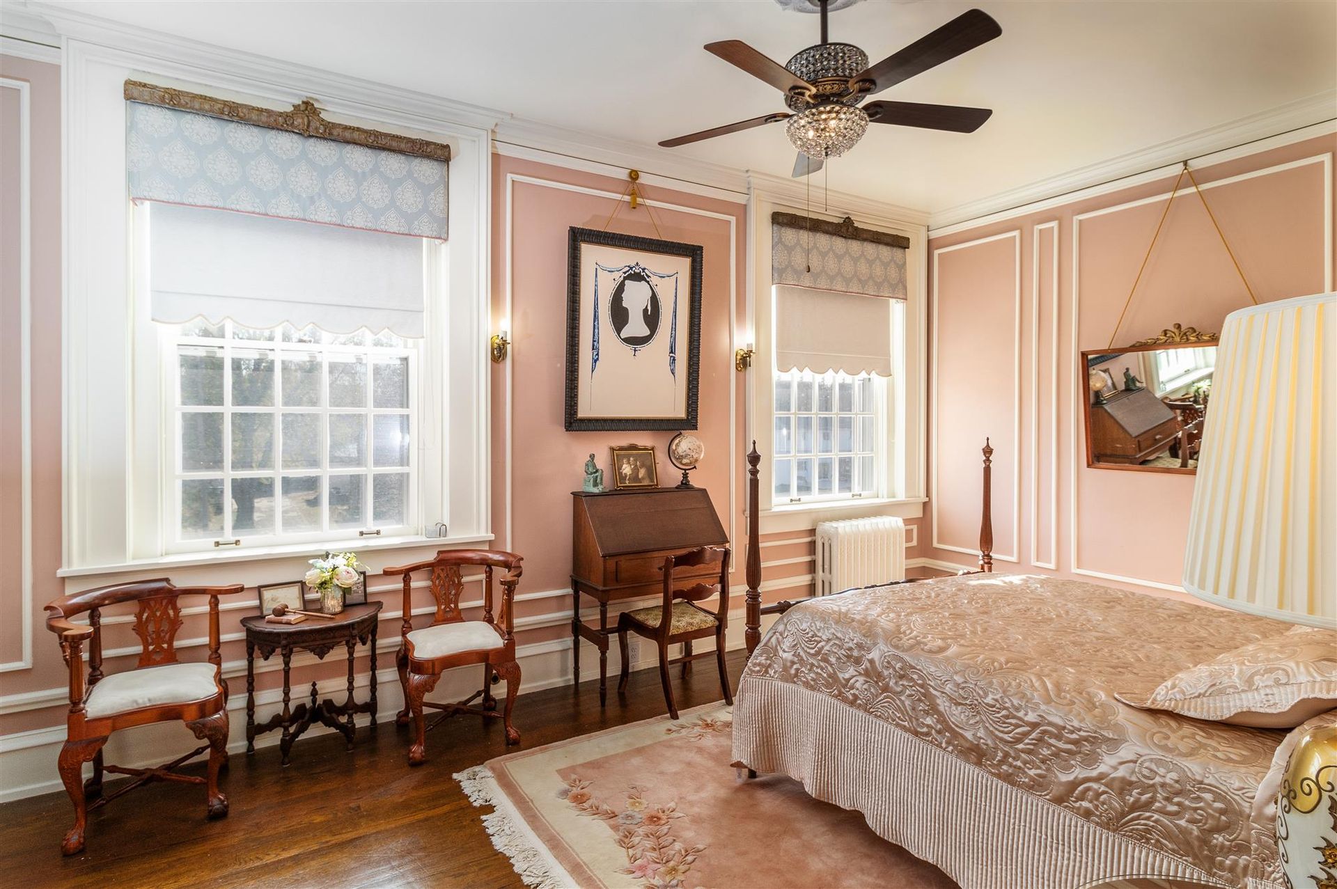 A bedroom with a bed , chairs , tables and a ceiling fan.
