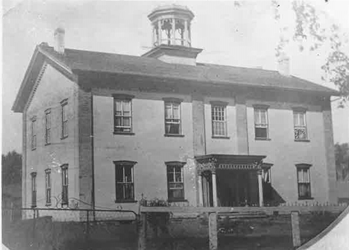 A black and white photo of a large brick building with a dome on top.