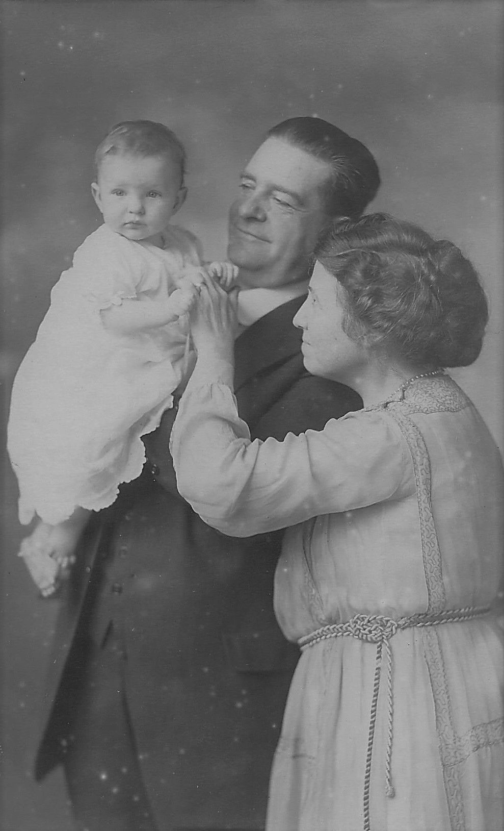 A black and white photo of a man and woman holding a baby.