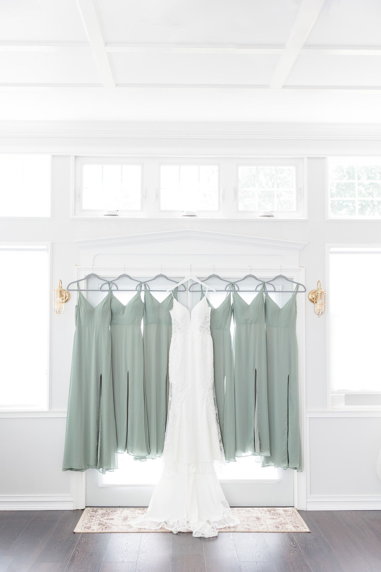 A wedding dress and bridesmaid dresses are hanging in a room.