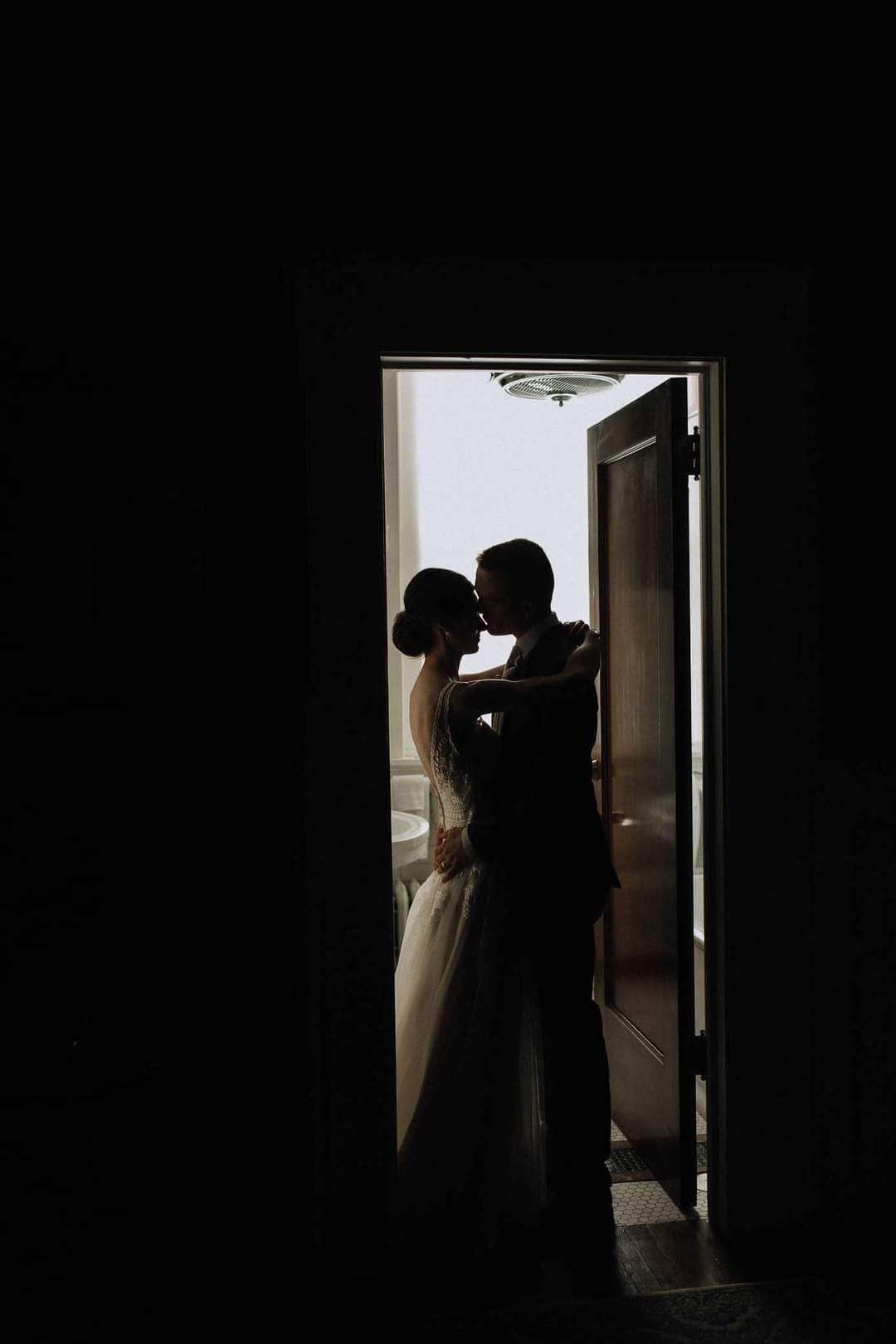 A bride and groom are kissing in a doorway.