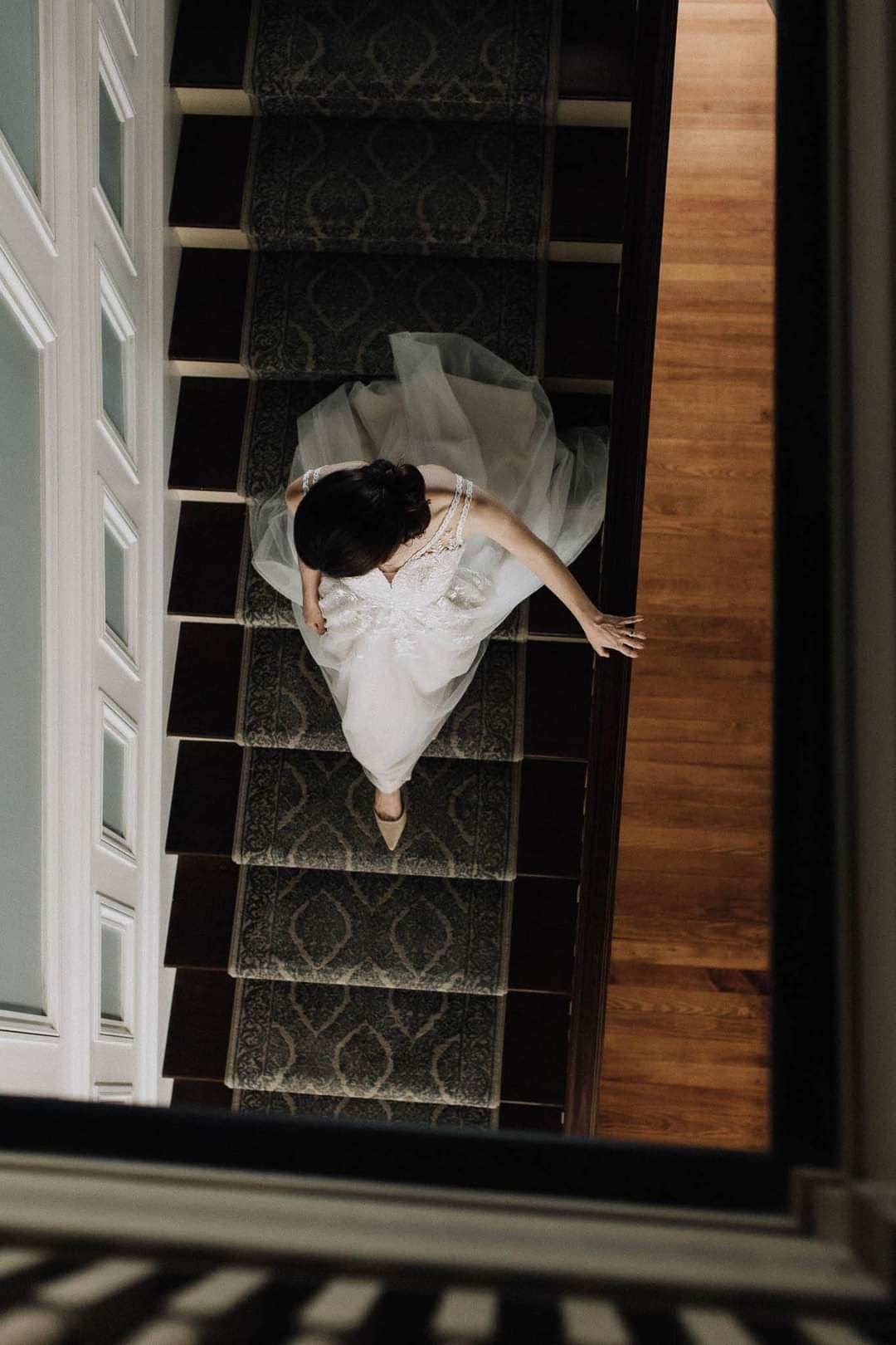 A woman in a wedding dress is walking down a set of stairs.