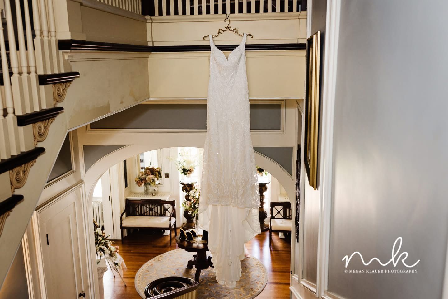 A wedding dress is hanging on a hanger in a hallway.