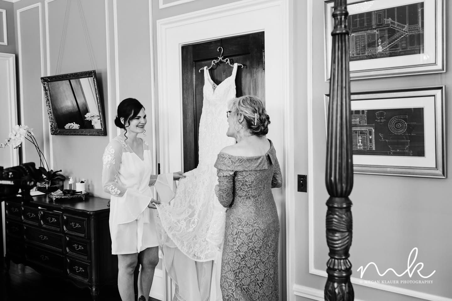A black and white photo of a bride and her mother getting ready for her wedding.