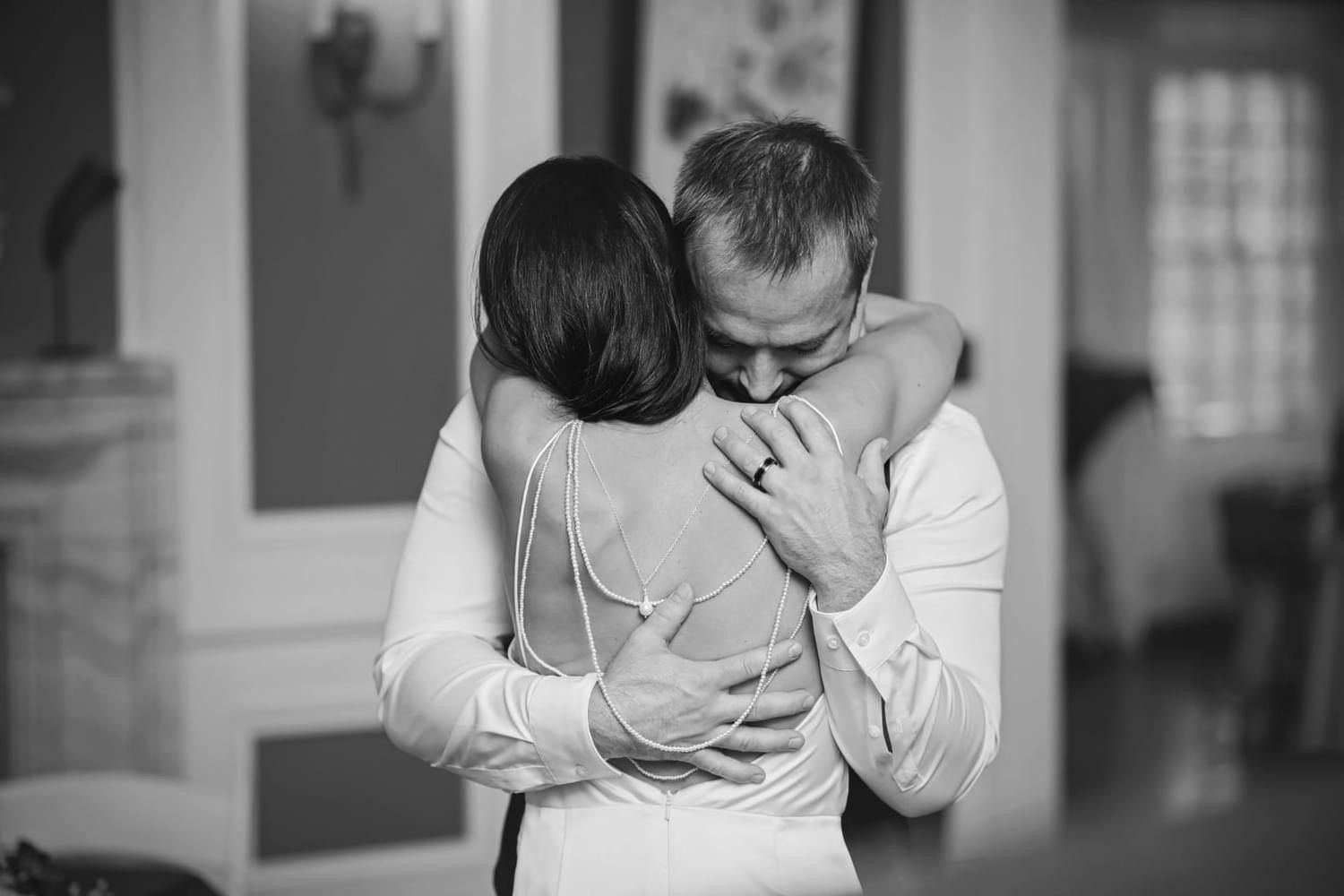 A bride and groom are hugging each other in a black and white photo.