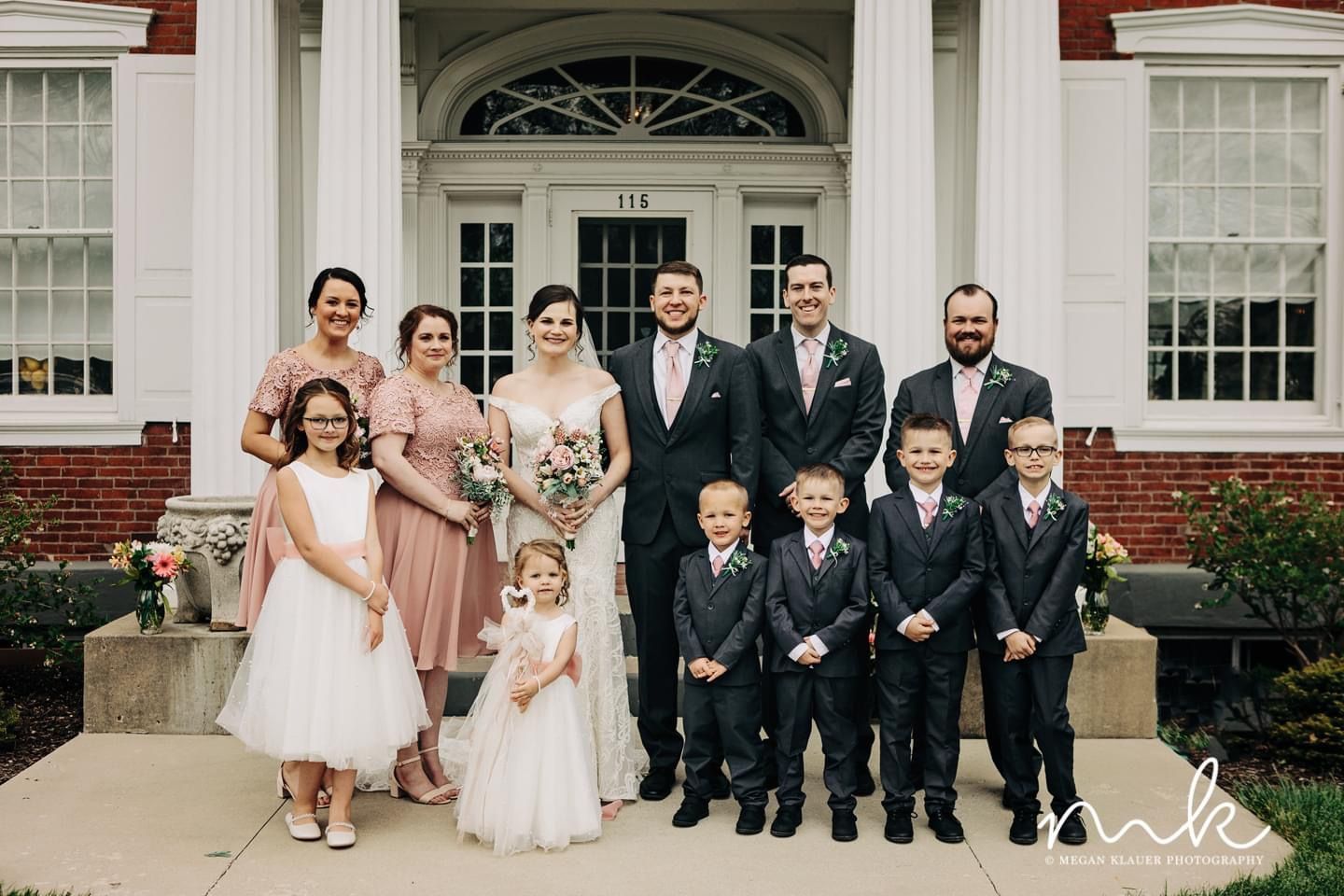 The bride and groom are posing for a picture with their wedding party.