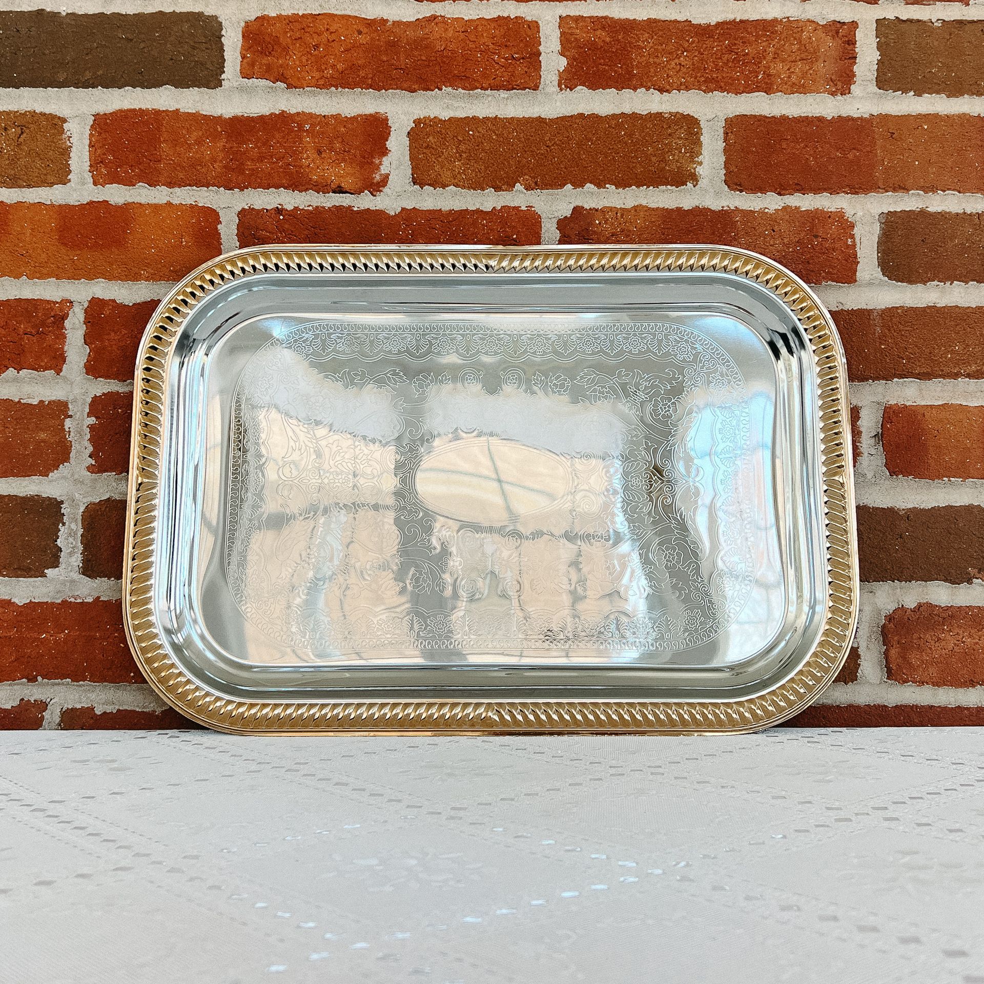 A silver tray with a gold rim sits on a table