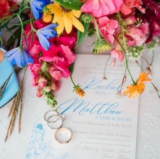 A wedding invitation for matthew and rachel sits next to a bouquet of flowers