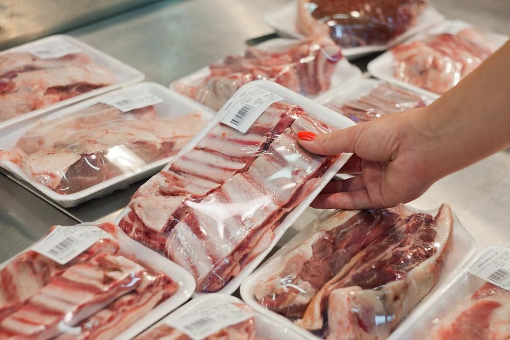 A Person Is Holding a Tray of Pork in A Store — Holiday Coast Meat & Smallgoods in Glenn Innes, NSW