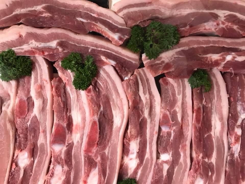 A Close up Of a Pile of Raw Pork Ribs with Parsley on Top — Holiday Coast Meat & Smallgoods in Glenn Innes, NSW
