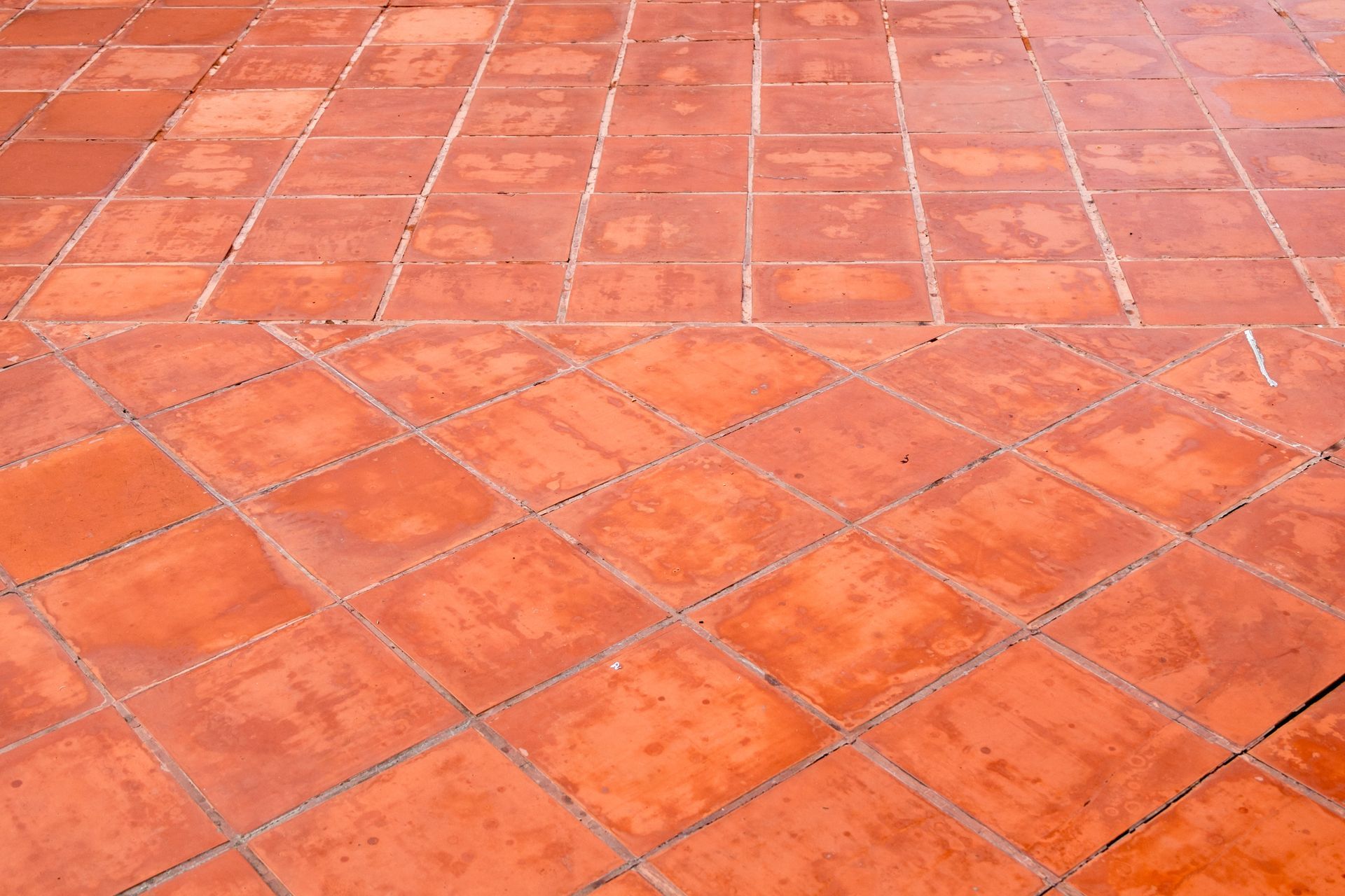 Primo piano di un pavimento piastrellato rosso con motivo a rombi.
