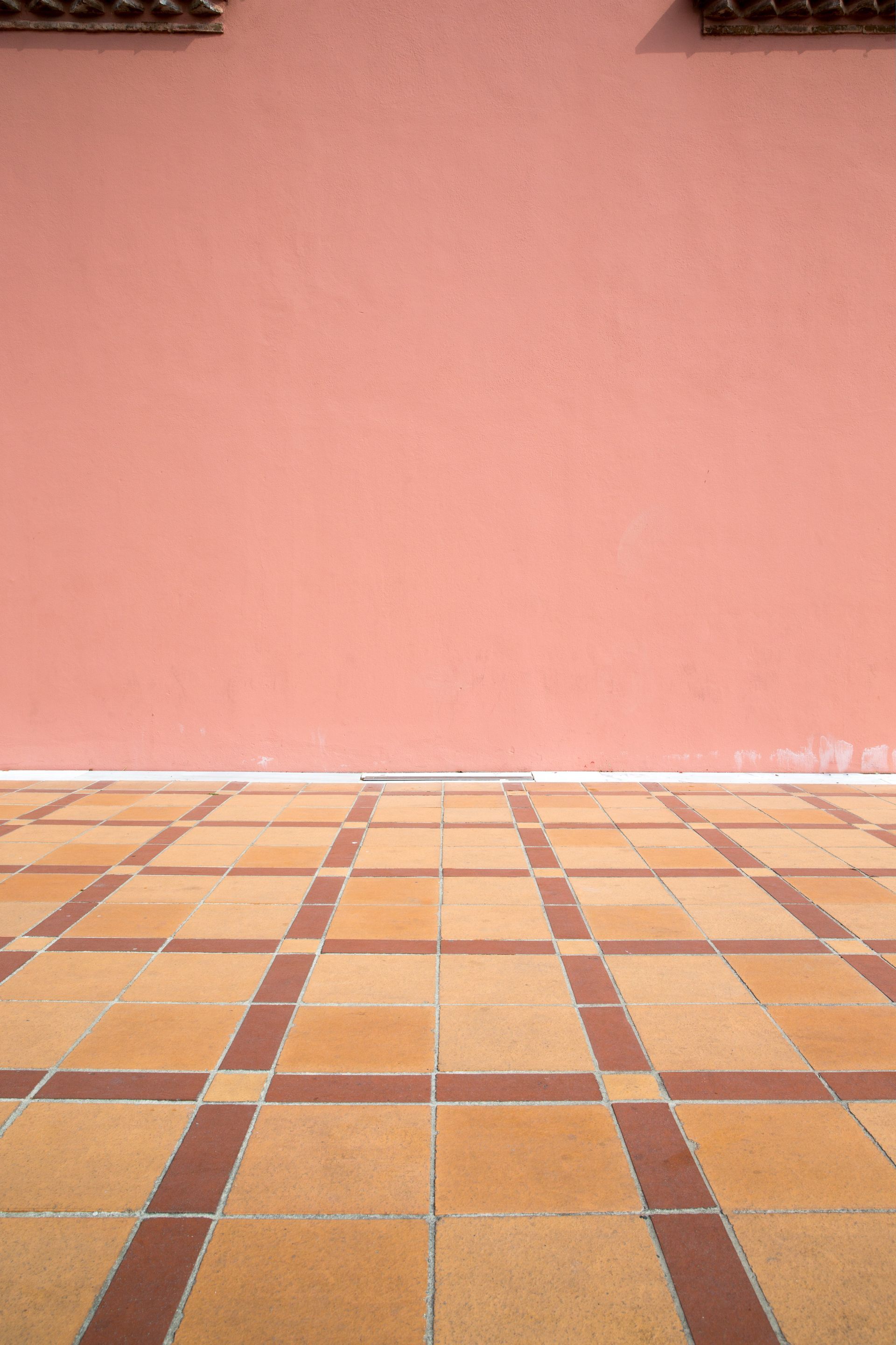 Un pavimento piastrellato davanti a una parete rosa.