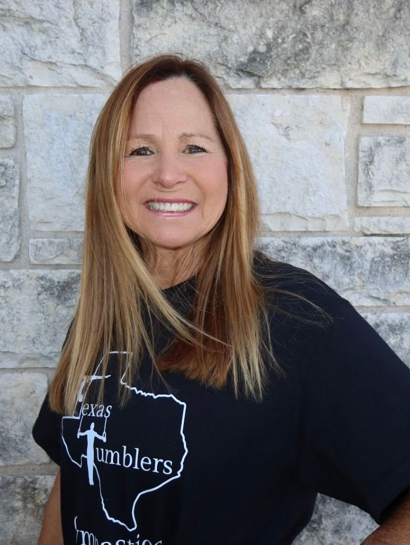 A woman in an orange shirt is smiling for the camera.