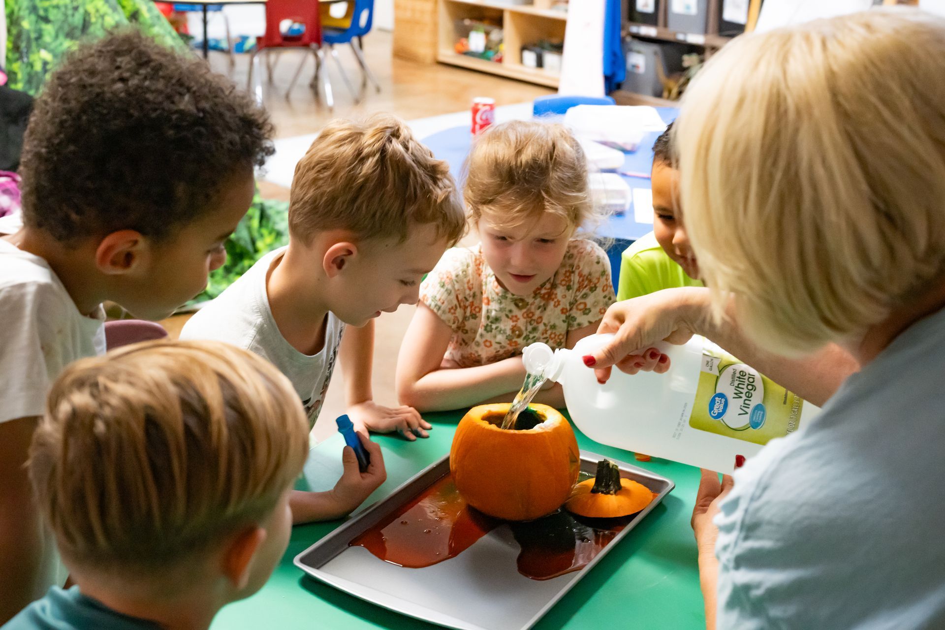 A group of children are standing in a circle with their heads together and smiling.