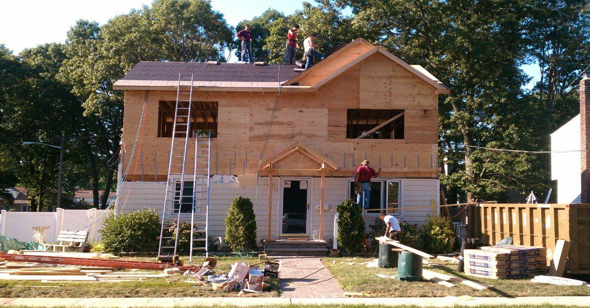 House under construction, workers on roof and scaffolding, exterior.