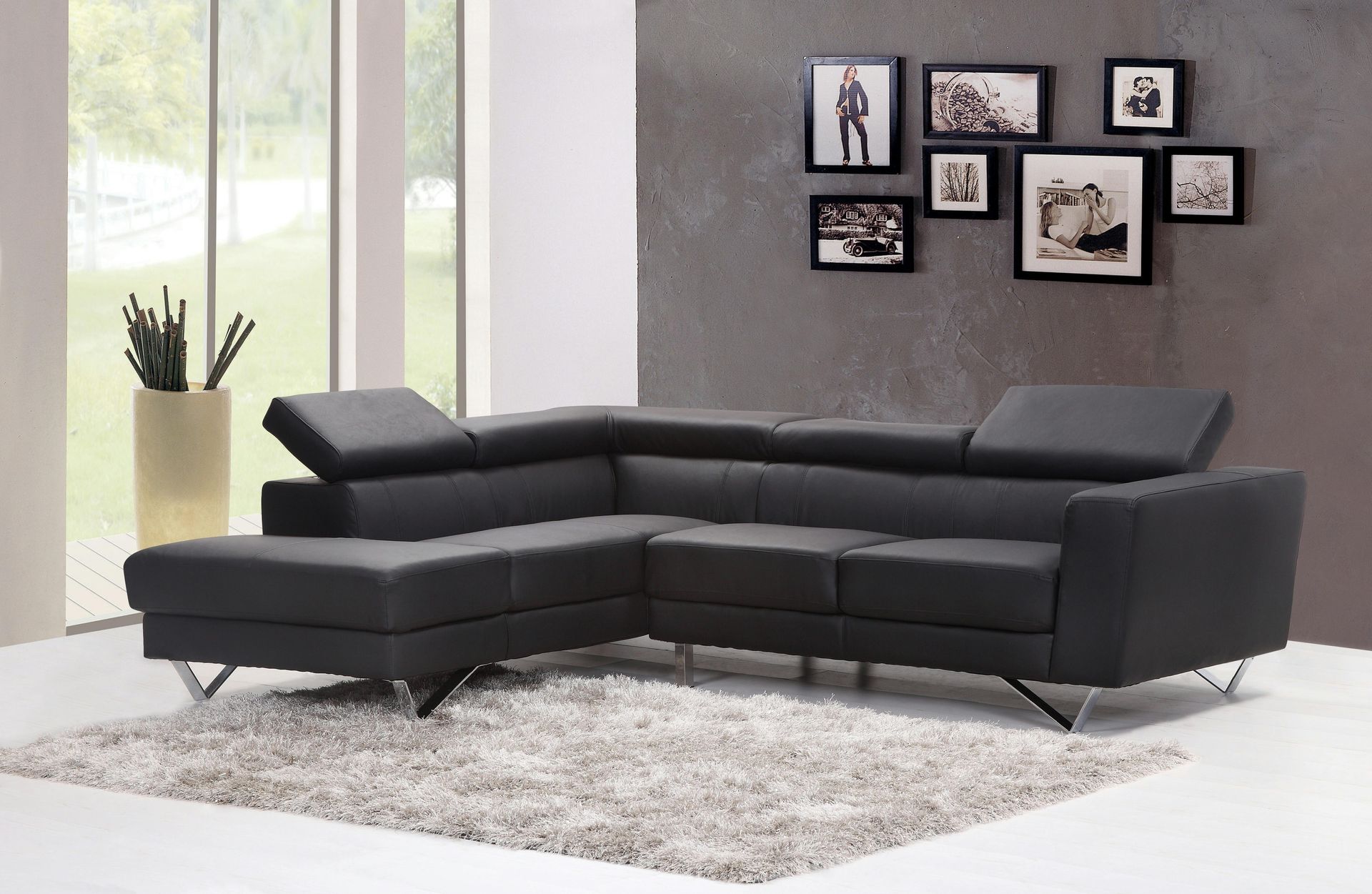 A living room with a black sectional couch and pictures on the wall