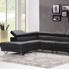 A living room with a black sectional couch and pictures on the wall