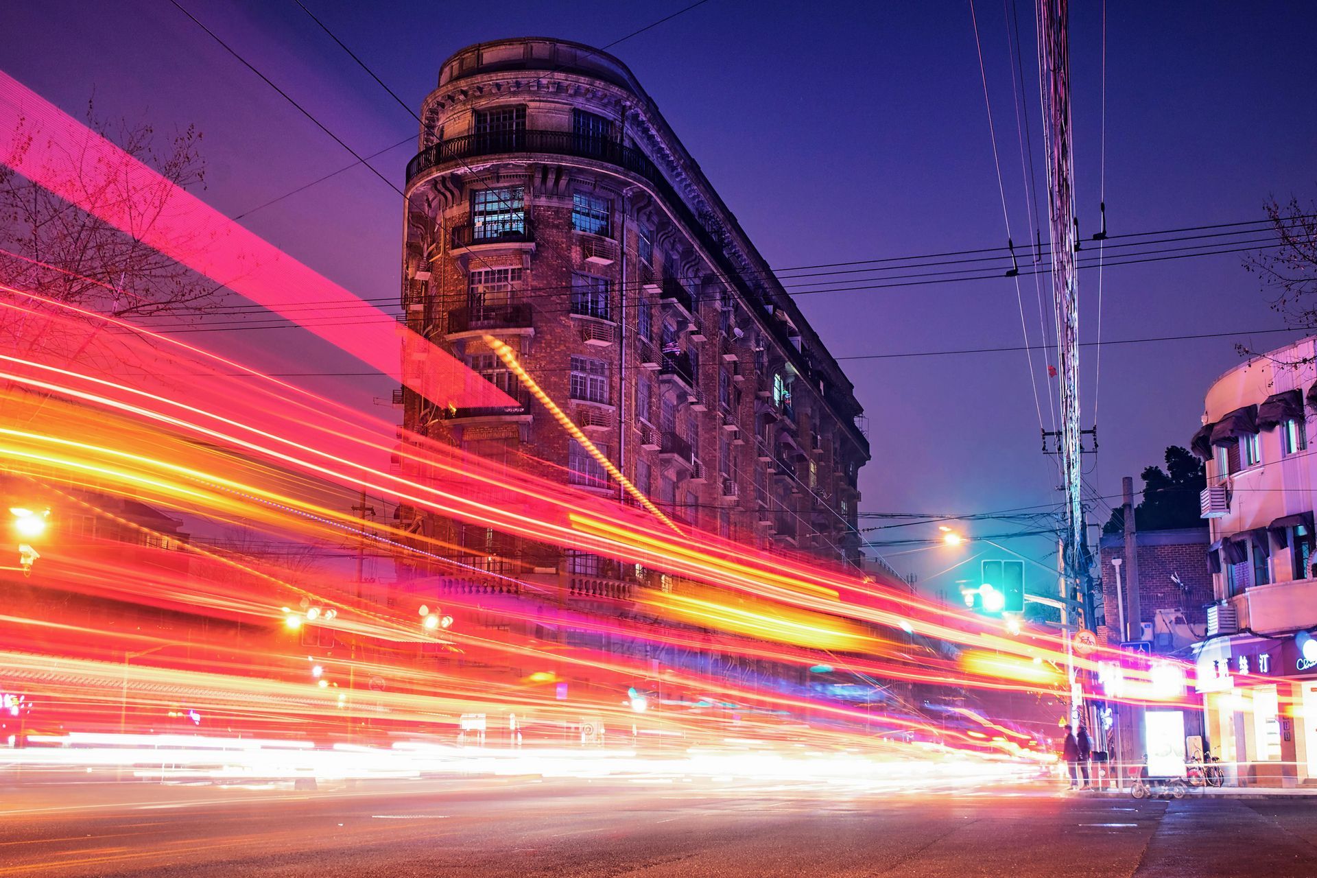 A long exposure photo of a city street at night with a building in the background.