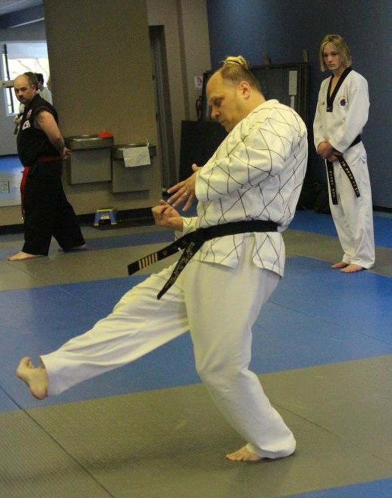 A man in a white karate uniform with a black belt