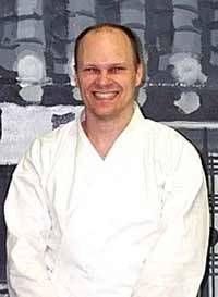 A man in a white karate uniform is smiling for the camera.