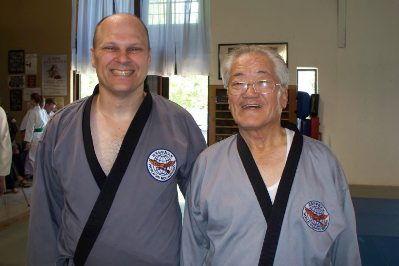 Two men in martial arts uniforms pose for a picture
