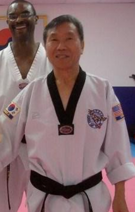 A man in a white karate uniform with a black belt