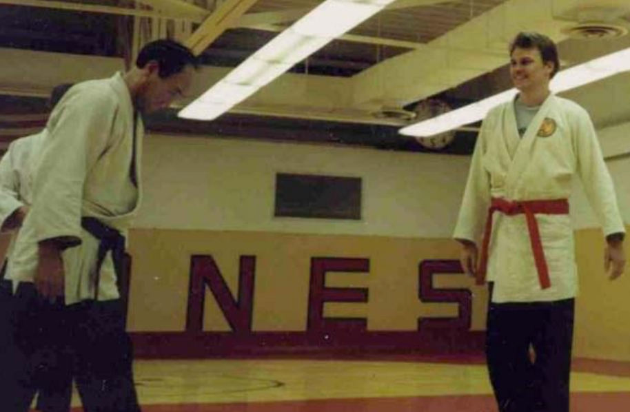 Two men are standing in front of a wall that says nes