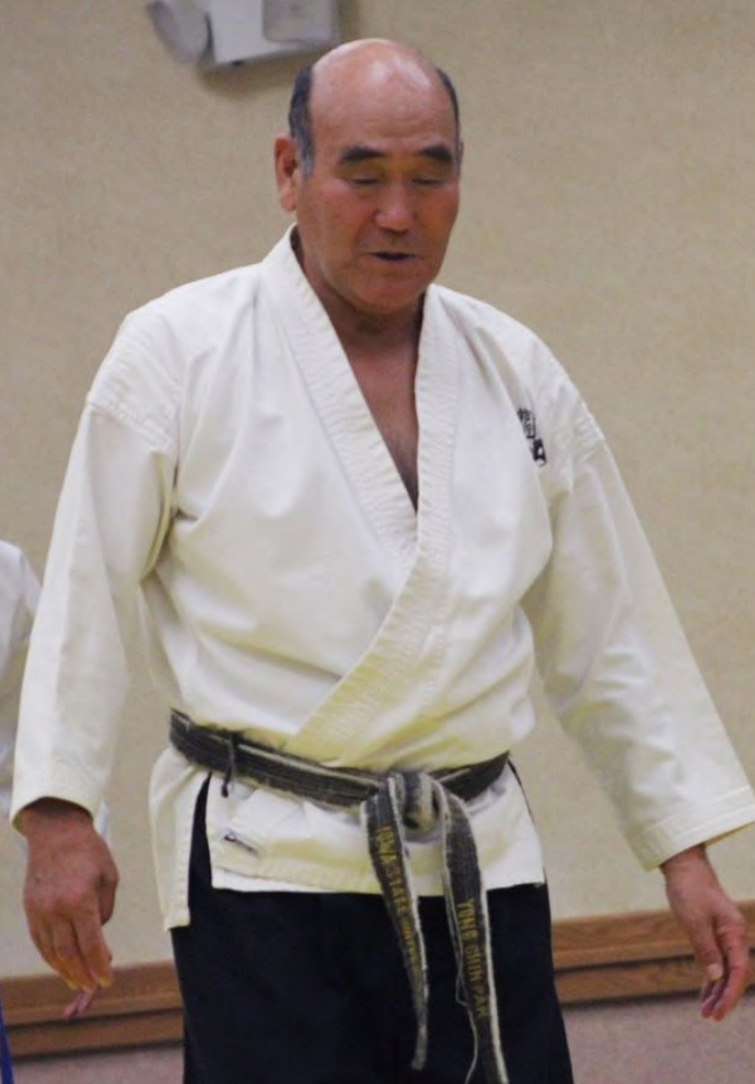 A man in a white karate uniform with a black belt