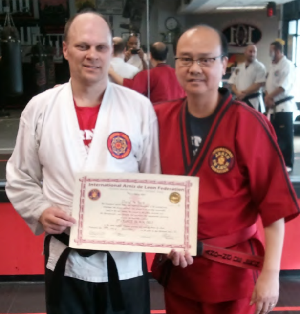 Two men in martial arts uniforms holding a certificate
