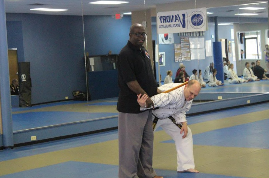 Two men are practicing martial arts in a gym with a sign that says virginia on it