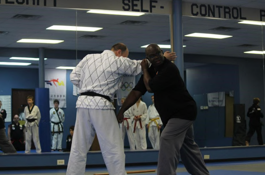 Two men are fighting in front of a sign that says self control