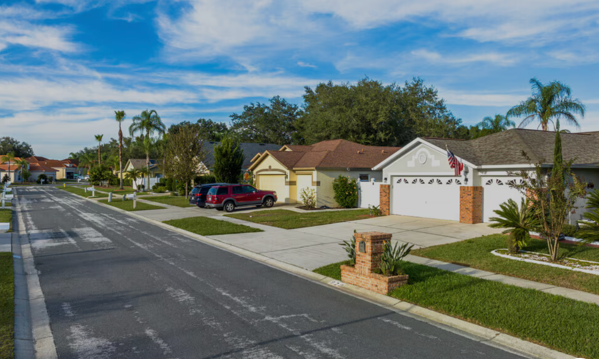 Residential street in Valrico, Florida  with houses, driveways, cars, and landscaping under a blue sky.