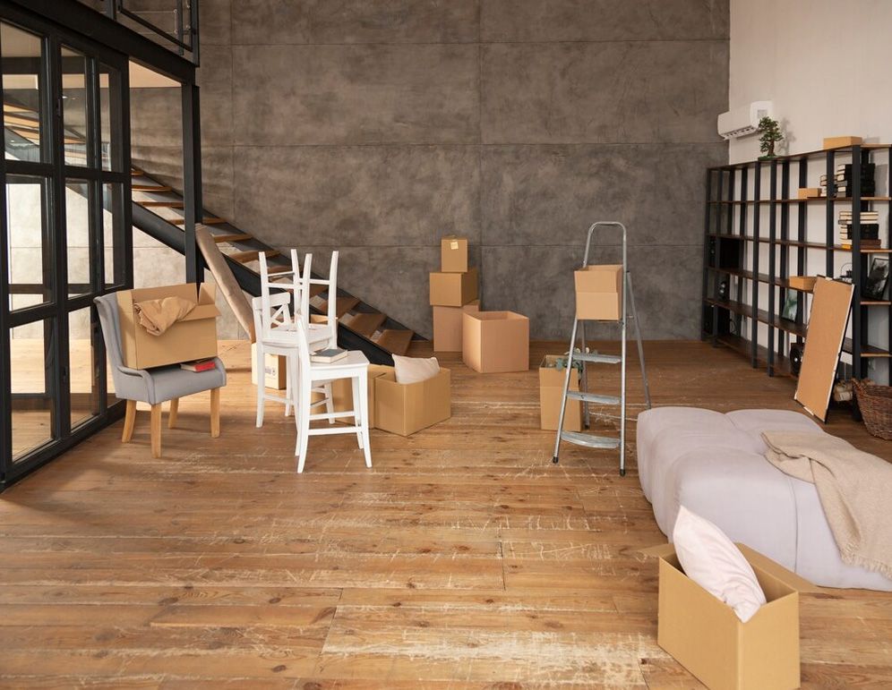 Room with moving boxes, furniture, and a stepladder; preparing for a move.