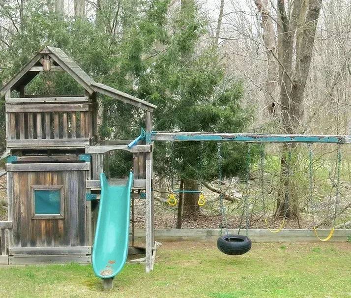 Wooden backyard playset with slide, swings, and tire swing.