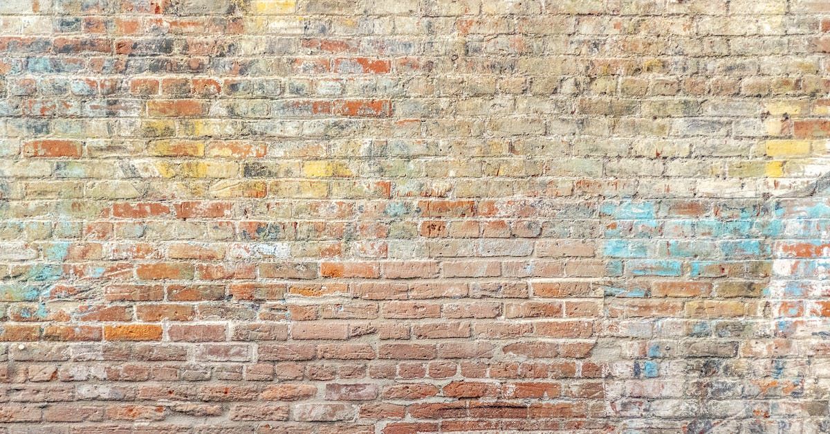 Brick wall, weathered with exposed bricks, faded colors, and textured surface.