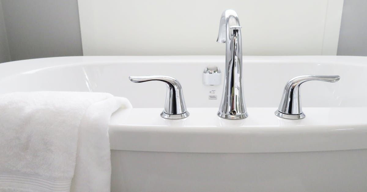 White bathtub with silver faucet and handles. White towel is draped on the side.