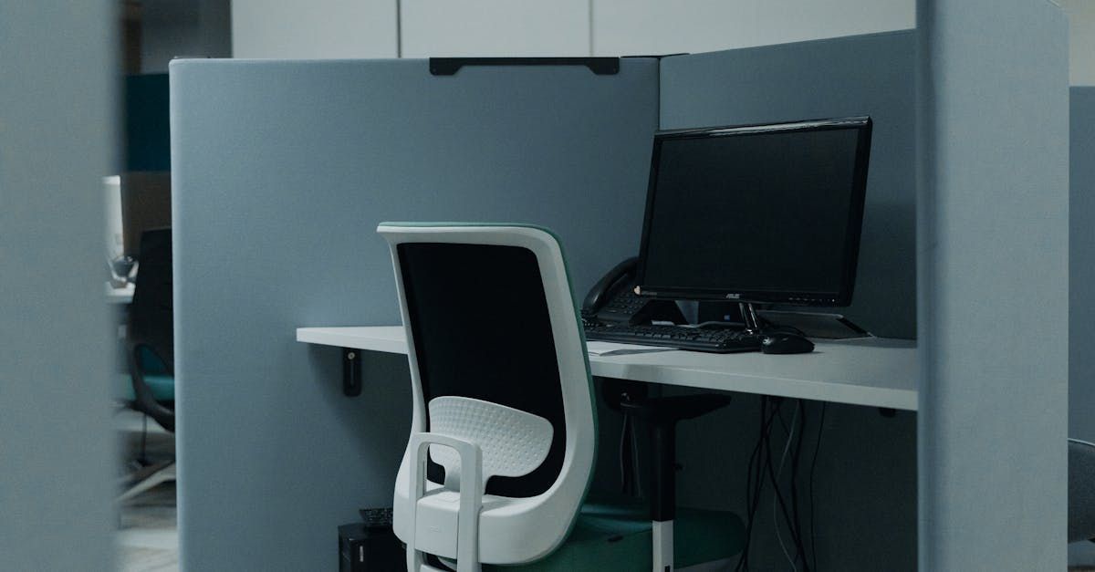 Office cubicle with computer monitor, chair, and desk. Gray and white colors dominate the scene.