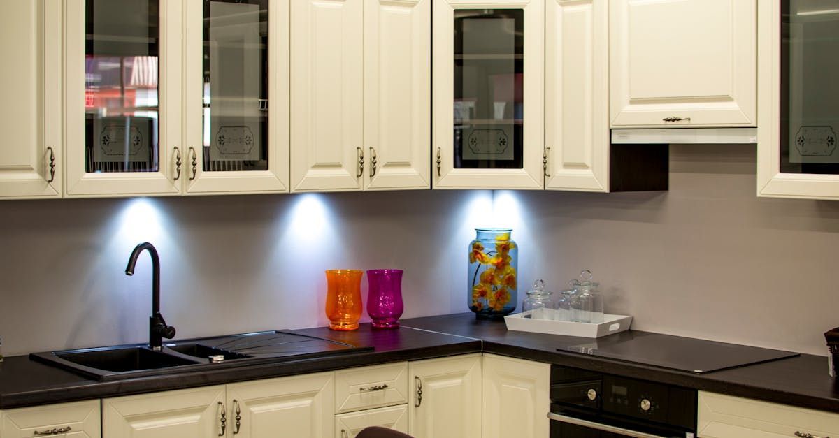 White kitchen with black countertops, cabinets, and sink. Under-cabinet lighting illuminates decor.