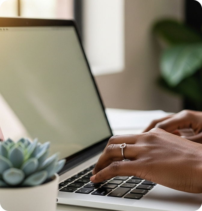 Hands typing on a laptop with a succulent in the foreground.