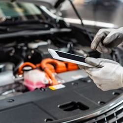 a person is holding a tablet in front of a car engine .