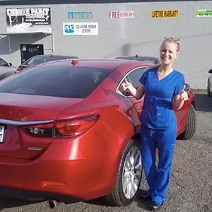 a woman in blue scrubs is standing next to a red car .