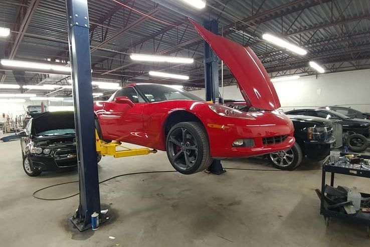 a red corvette is sitting on a lift in a garage .