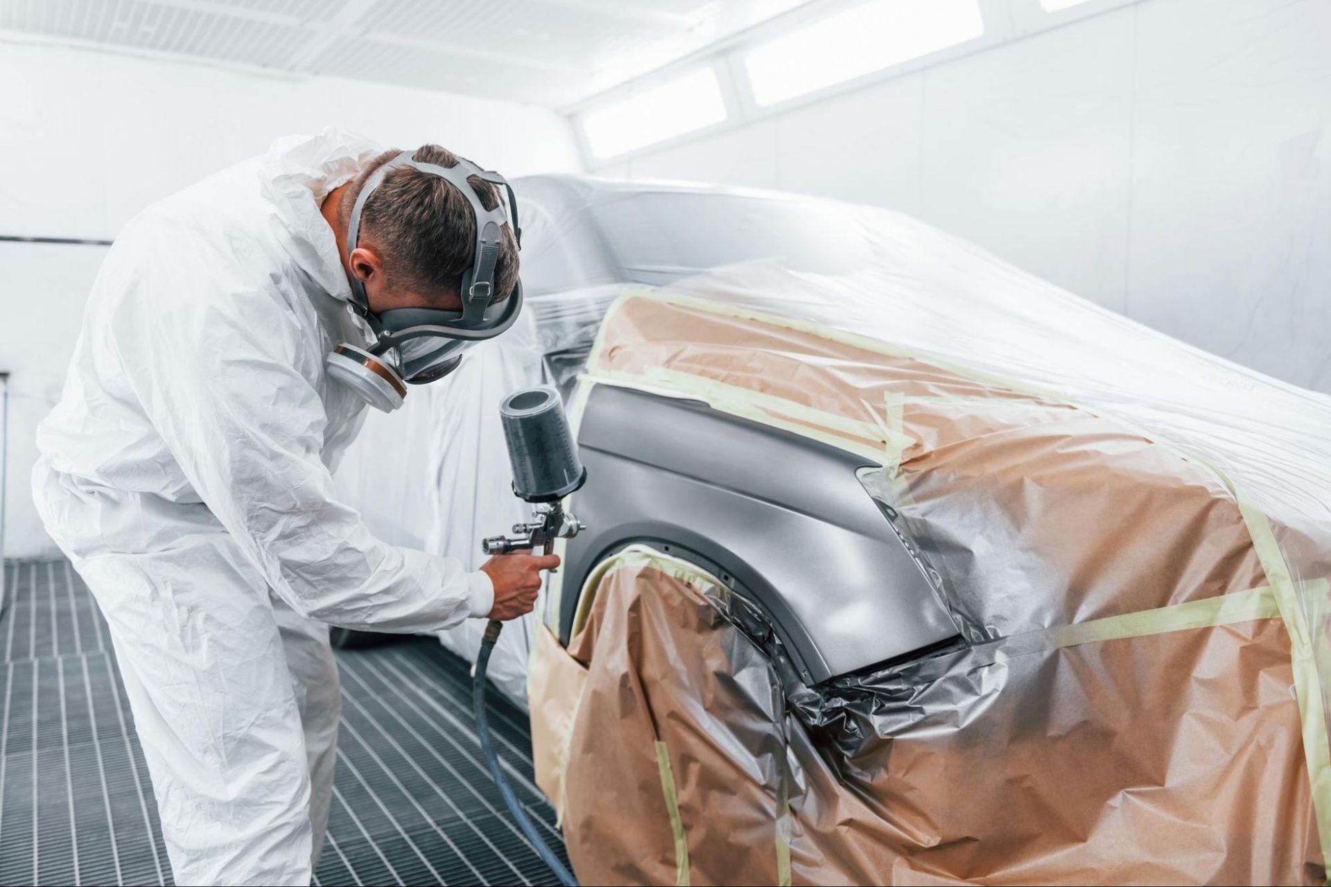 a man is painting a car in a paint booth .